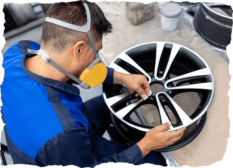 Worker sanding an alloy wheel at a car part factory
