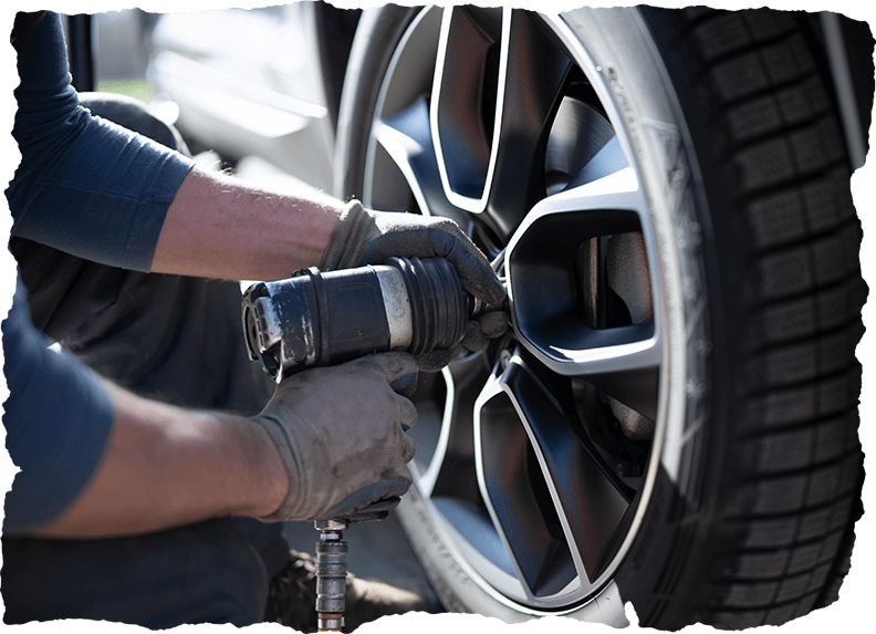 Close-up shot of an unrecognizable auto repairman changing whleel and tire in a workshop